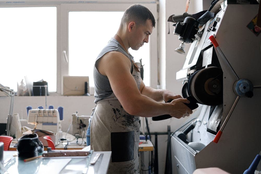 A workbench with leather boots being worked on by hand