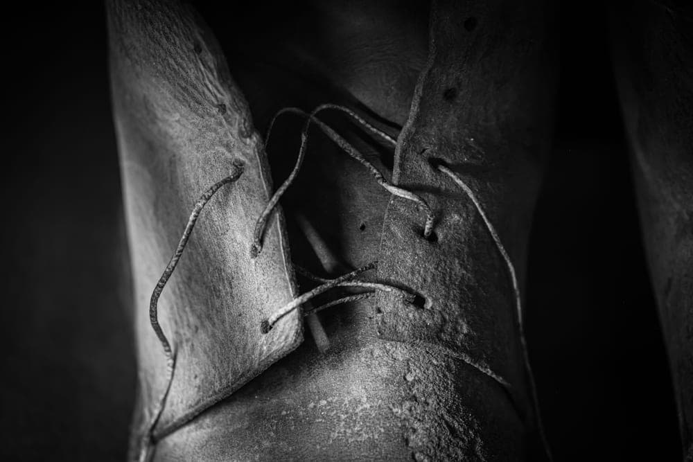 Close detail of a worn leather boot with the laces and eyelets visible